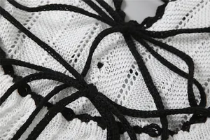 Close-up of white crochet knit fabric with contrasting black tie-up drawstring details