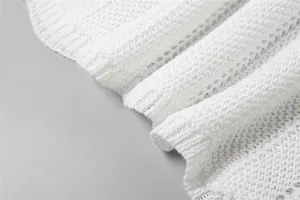 Macro view of white hollow-out knit fabric texture showing intricate crochet patterns.
