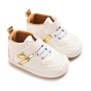 Detailed view of white infant soft sole sneakers with gold accents and velcro straps