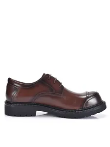 Dettaglio laterale di scarpe Derby in pelle marrone classica con punta e suola spessa.