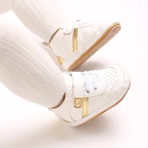 Detailed view of white infant walking shoes with gold accents and velcro straps