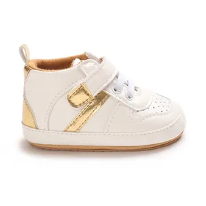 Side view detail of baby white sneakers with metallic gold accents and soft sole