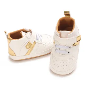 Close-up of white baby walking shoes with gold accents and velcro straps