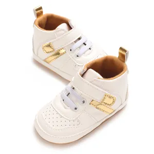 Detailed close-up view of white baby sneakers featuring gold accents and velcro straps