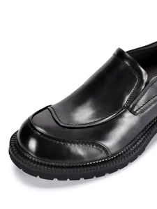 Primer plano de zapatos mocasines para hombre en cuero genuino negro con suelas gruesas.