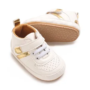 Close-up of white baby walking shoes with gold accents and soft non-slip rubber soles.