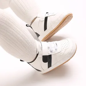 Detailed close-up of white baby walking shoes with soft soles and black stripe details