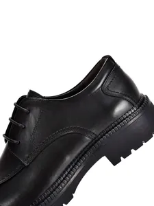 Dettaglio ravvicinato di scarpe stringate in pelle nera da uomo con una suola spessa