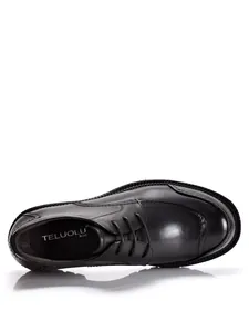 Vista dall'alto di scarpa derby in pelle nera con suola spessa e design stringato