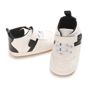 Detailed view of white baby walking shoes featuring black accents and soft rubber soles