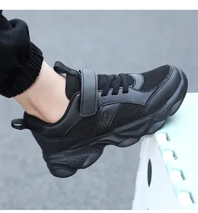 Primer plano de zapatillas negras para niños con malla transpirable y cierre de velcro.