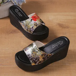 Close-up detail of women's floral print wedge slippers with thick black platform soles