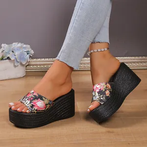 Close-up shot of black platform wedge sandals featuring a vibrant floral pattern strap