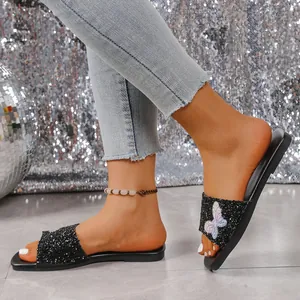 Dettaglio dei sandali piatti di paillettes con motivo a farfalla di strass colorati