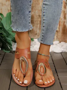 Primer plano de elegantes sandalias de dedo marrones para mujer con hebilla metálica ovalada