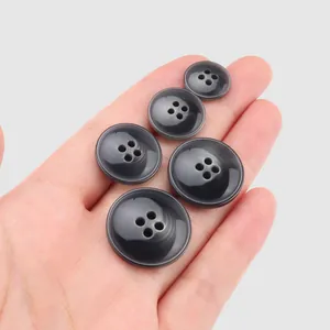 Lot de boutons en résine grise à 4 trous de tailles assorties posés sur une paume