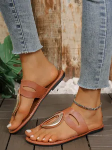 Detalle de las sandalias de dedo planas marrones para mujer con hebilla metalizada