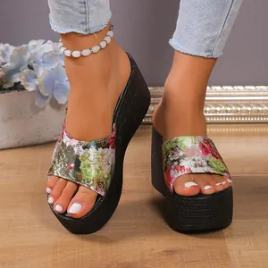 Close-up of stylish women's floral print wedge platform sandals worn on model's feet.