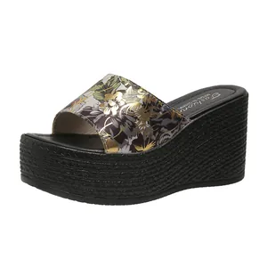 Side view of black wedge sandals with floral print strap and woven platform texture