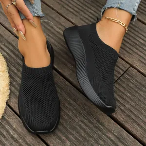 Close-up of black breathable knit slip-on sneakers on a wooden deck
