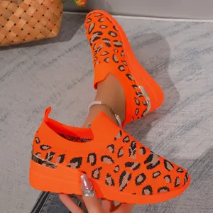 Detail view of orange leopard print flyknit wedge sneakers with metallic heel accent