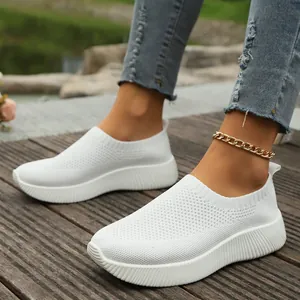 Close-up of white breathable fly-knit mesh sneakers for women on an outdoor wooden deck