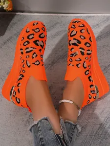 Detailed view of women's orange leopard print sneakers with fly-knit upper and wedge heel