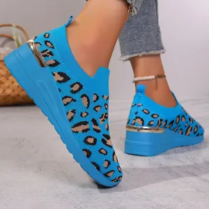 Close-up of blue leopard print fly-knit wedge sneakers with metallic gold heel detail.
