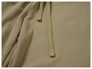 Close-up detail of khaki sweatpants featuring a flat knit drawstring and soft jersey fabric.