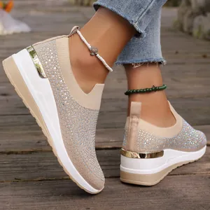 Dettaglio di sneakers beige con zeppa con strass e finiture dorate sul tallone