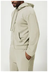 Vista laterale di una felpa beige con cappuccio e zip e pantaloni coordinati da uomo