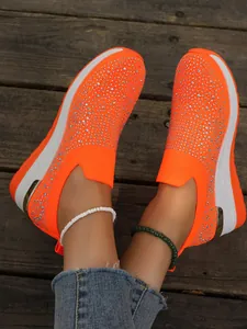 Sneaker slip-on arancioni vivaci con strass e suola a zeppa bianca spessa e moderna