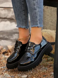 Primer plano detallado de zapatos Oxford de charol negro brillante con plataforma y suela gruesa