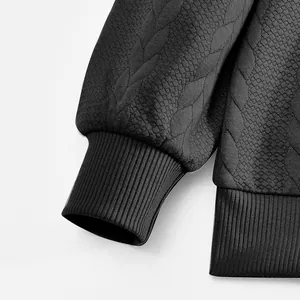 Nahaufnahme des schwarzen Strick-Sweatshirts mit gerippten Bündchen und Textur