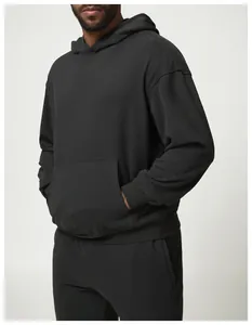 Detalle lateral de una sudadera con capucha negra de gran tamaño y pantalón de chándal
