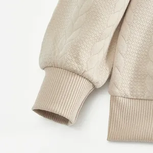 Detailansicht der Rippbündchen und Jacquard-Textur eines beigen Retro-Freizeit-Sweatshirts.