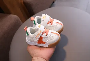 Close-up of breathable white and orange toddler walking shoes with velcro straps.