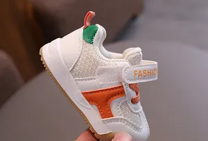Close-up of white toddler walking shoes with breathable mesh and orange accents