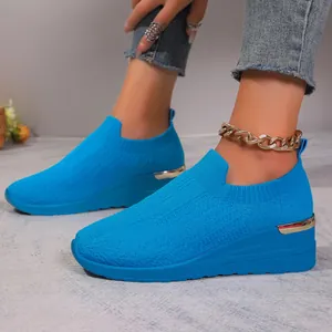 Close-up detail of breathable blue fly-knit wedge sneakers with stylish metallic heel trim