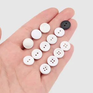 Variety of white and cream textured decorative resin buttons for clothing shown in hand