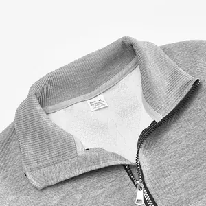 Nahaufnahme des Stehkragens und Reißverschlusses eines grauen Jacquard-Strickpullovers