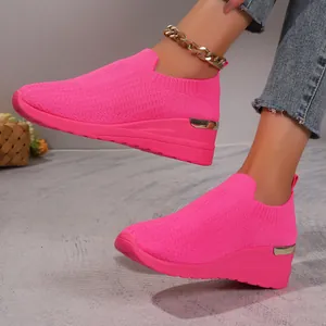 Detailed view of women's vibrant hot pink breathable mesh wedge sneakers on feet