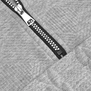Makrodetail des Metallreißverschlusses und der grauen Jacquard-Strickstruktur des Hoodies.