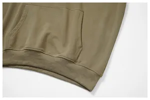 Detalle de primer plano de sudadera caqui con bolsillo canguro y bajo elástico tejido