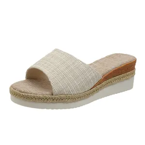 Détail d'une sandale compensée en tissu texturé avec semelle à tresse dorée pour femme