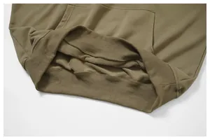 Primer plano del dobladillo acanalado de la sudadera verde oliva y el forro interior de felpa.
