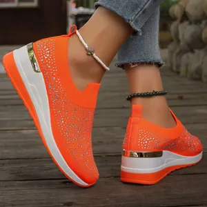 Primo piano di eleganti sneakers con zeppa arancioni con strass e finiture dorate