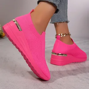 Close-up detail of vibrant pink fly-knit wedge sneakers featuring metallic gold heel trim