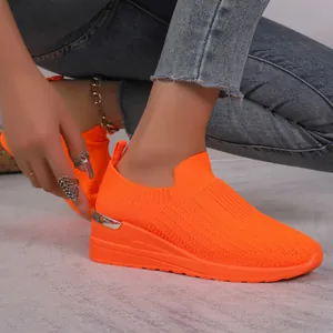 Side view detail of bright orange breathable fly knit mesh wedge sneaker for women