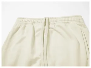 Detail shot of men's cream sweatpants featuring an elastic waistband and drawstring